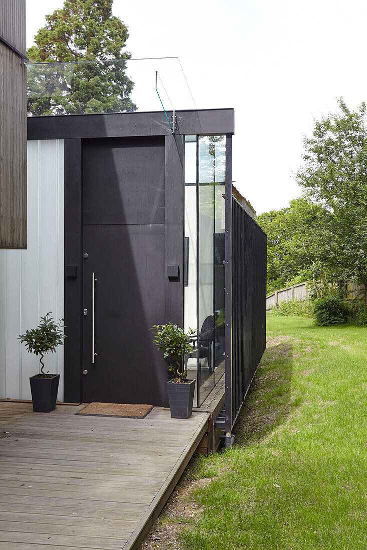 Black front door with pot plants and door mat to modern Isle of Wight home UK