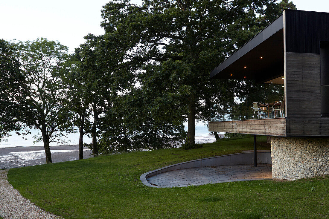 Modern facade with timber cladding and pebble-dashed lower storey with view to sea on Isle of Wight, UK