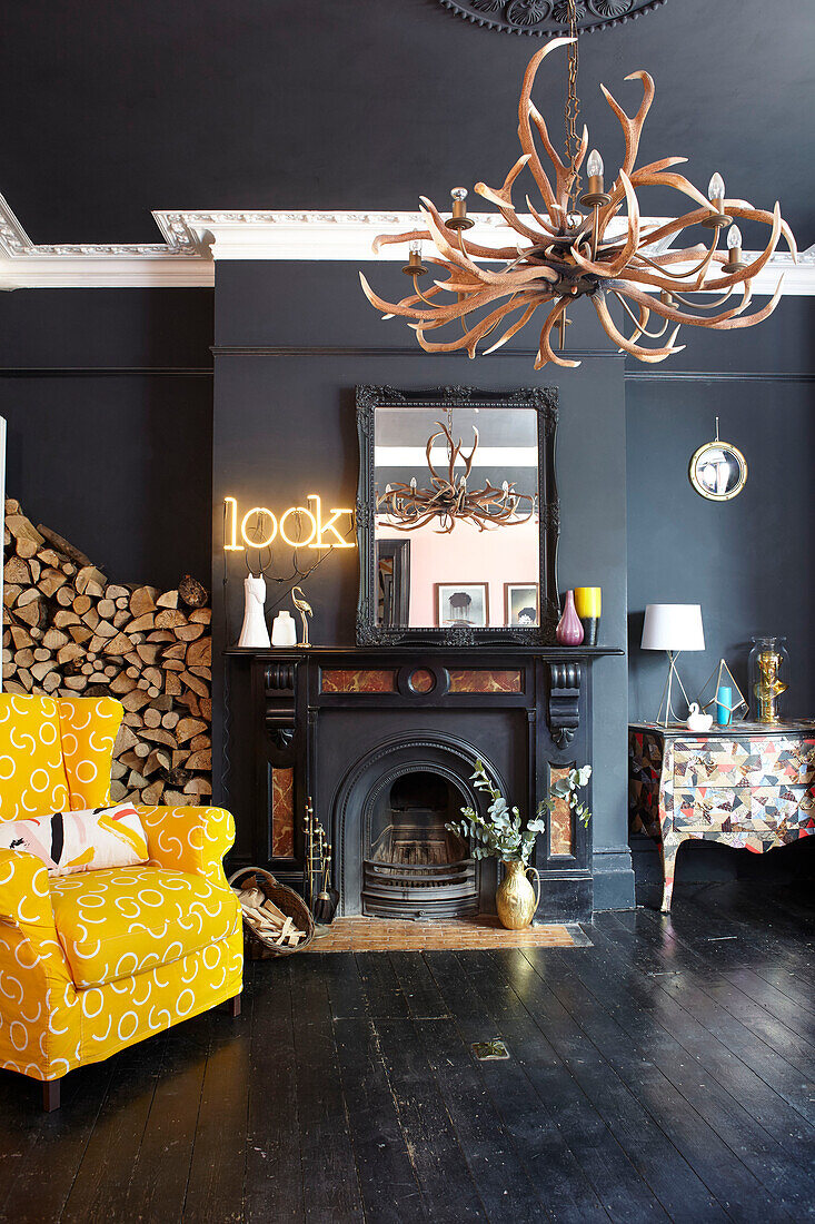 Yellow armchair with firewood in black living room of Hastings townhouse East Sussex England UK