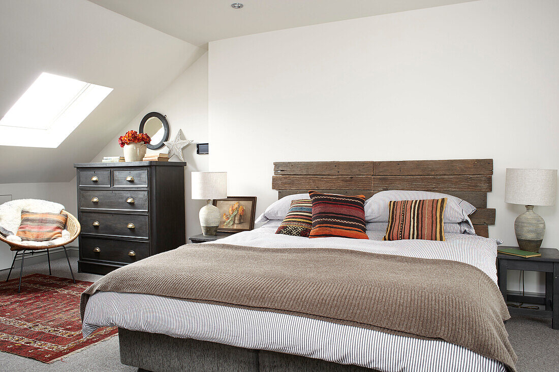 Gerettetes hölzernes Kopfteil mit brauner Wolldecke in einem Schlafzimmer im Dachgeschoss in Brighton, East Sussex, Großbritannien
