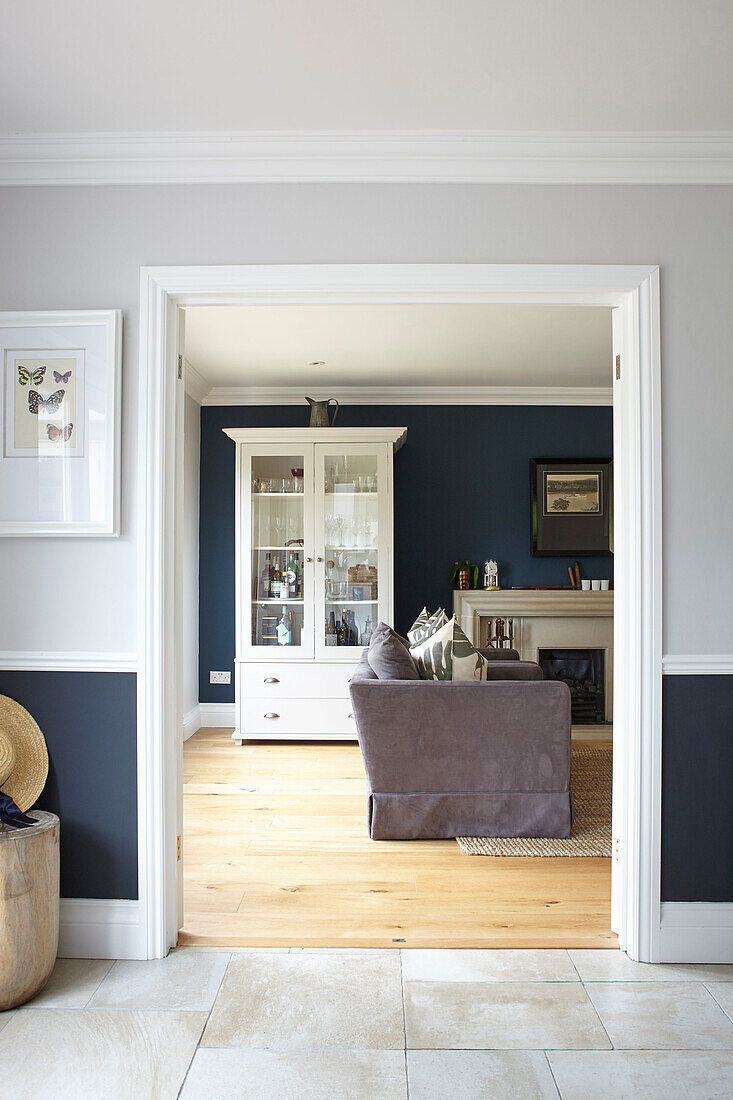 Blick durch eine Tür mit einer Kommode mit Glasfront und einem Sofa im Wohnzimmer von Hague Blue Buckinghamshire UK