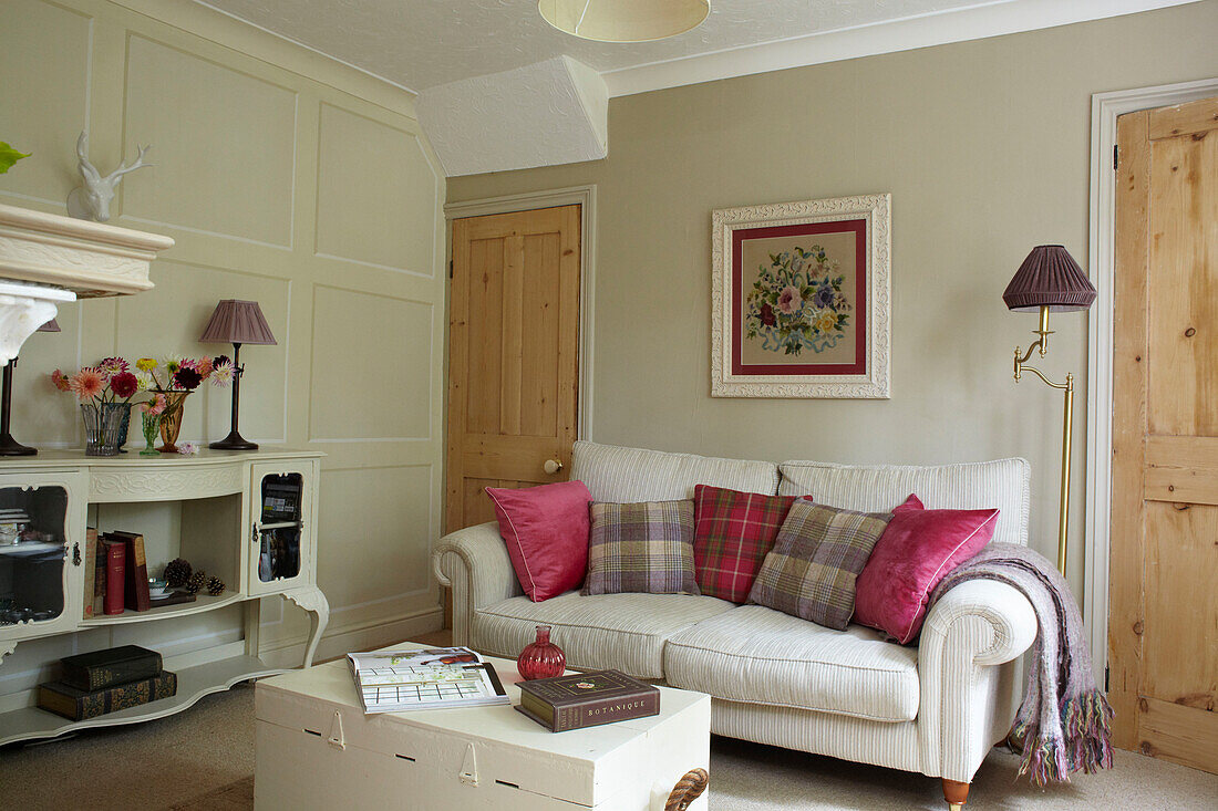 Pink and checked cushions on sofa in living room with painted sideboard, East Cowes home, Isle of Wight, UK