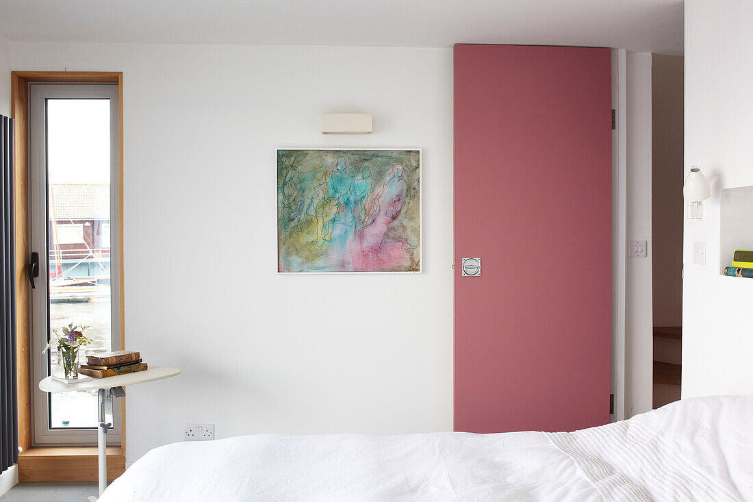 Pink door and artwork with window in bedroom of Bembridge houseboat Isle of Wight, UK