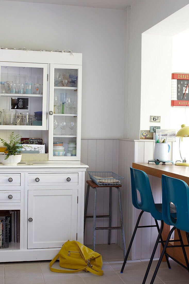 White painted kitchen dresser with yellow handbag and teal barstools in Ryde home Isle of Wight, UK