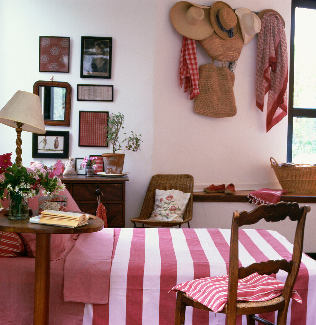Rosa und weißes Schlafzimmer im Landhausstil mit Strohhüten an der Wand