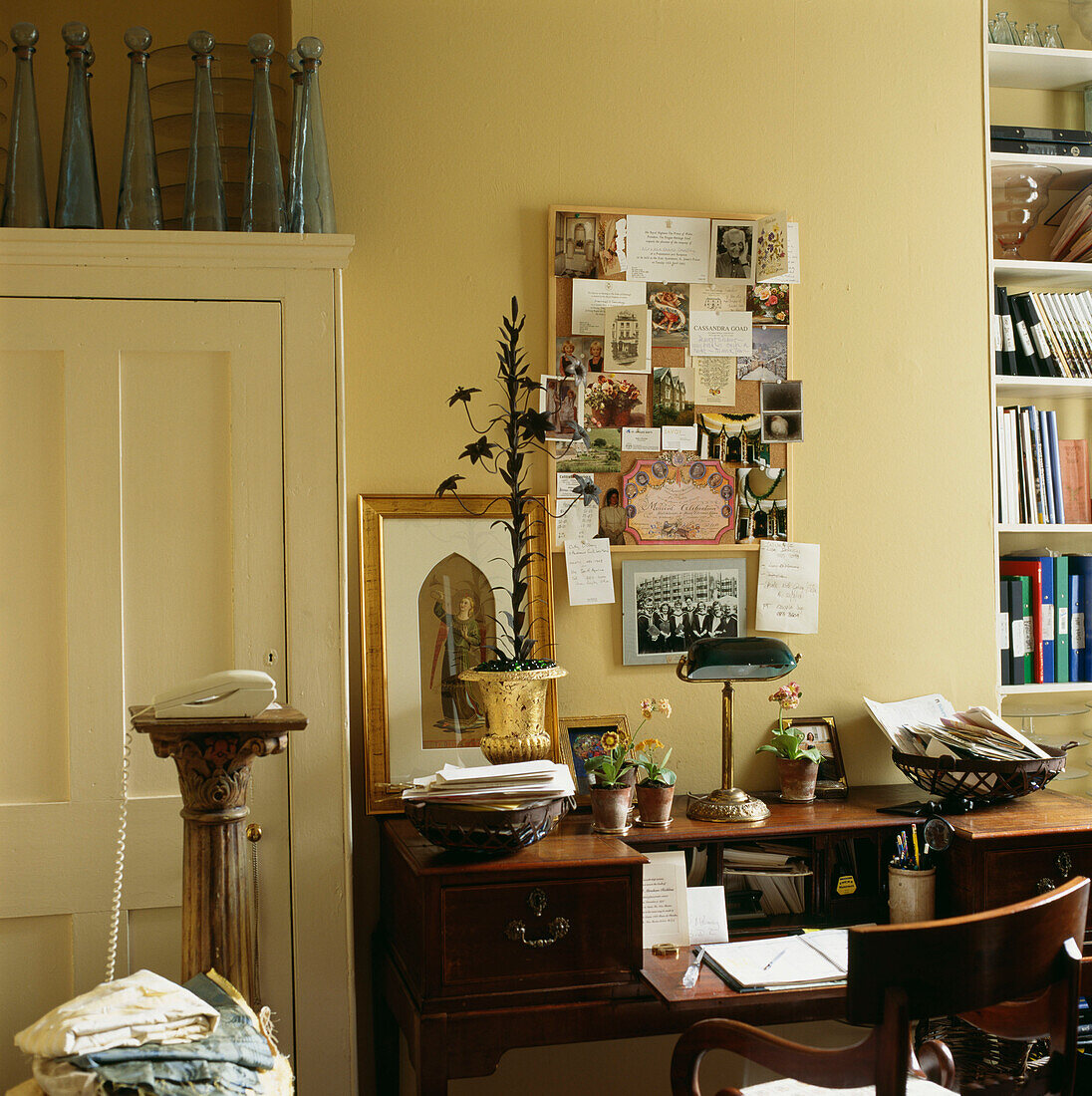Schreibtisch und Stuhl mit Pinnwand und diversem Papierkram im Arbeitszimmer