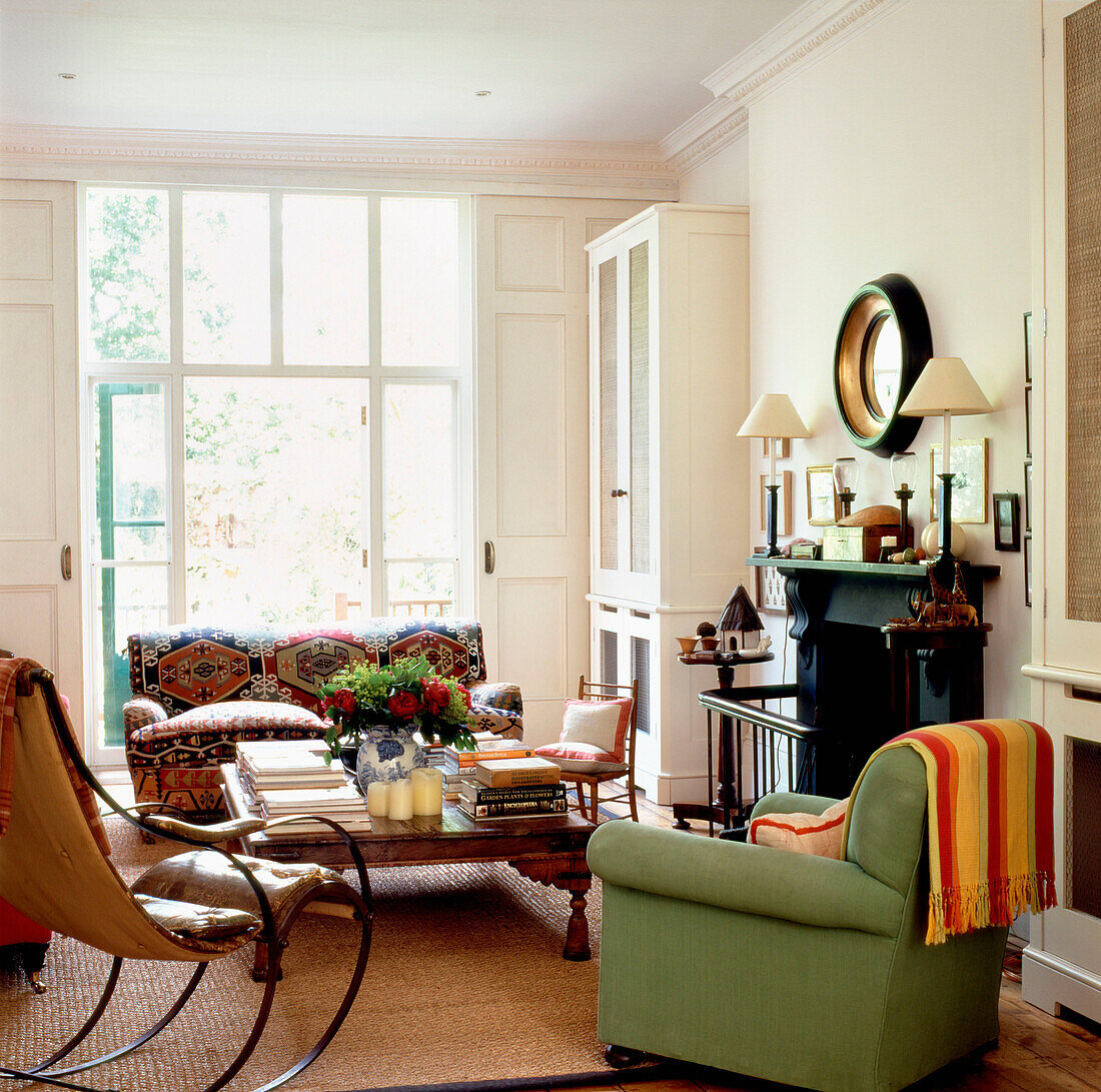 Wohnzimmer mit hellgrünem Sessel und niedrigem Ethno-Couchtisch vor einem sonnigen französischen Fenster