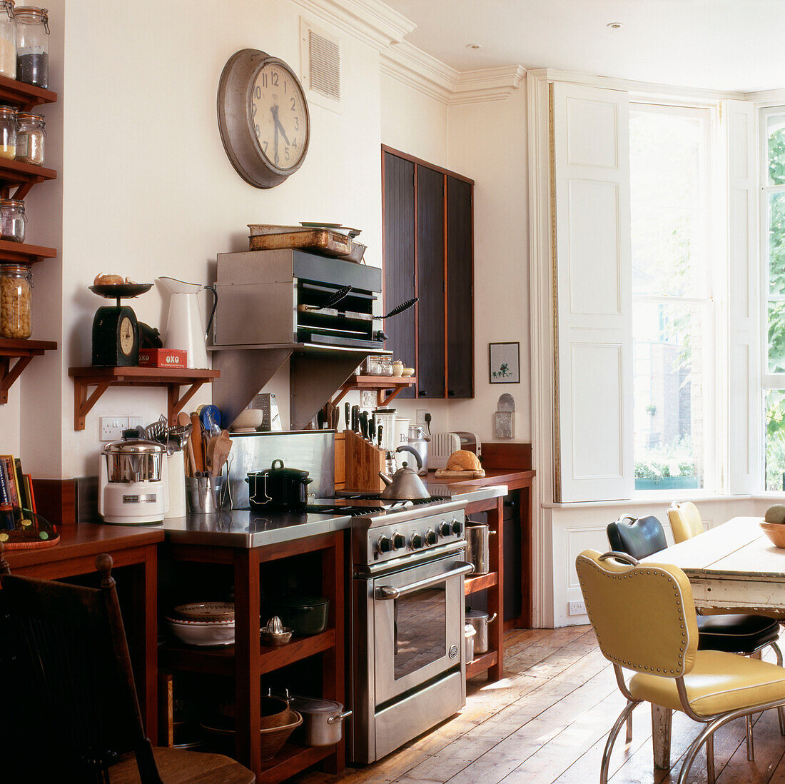 Kitchen with stained black wooden cupboards and built in open shelves and stripped floorboards