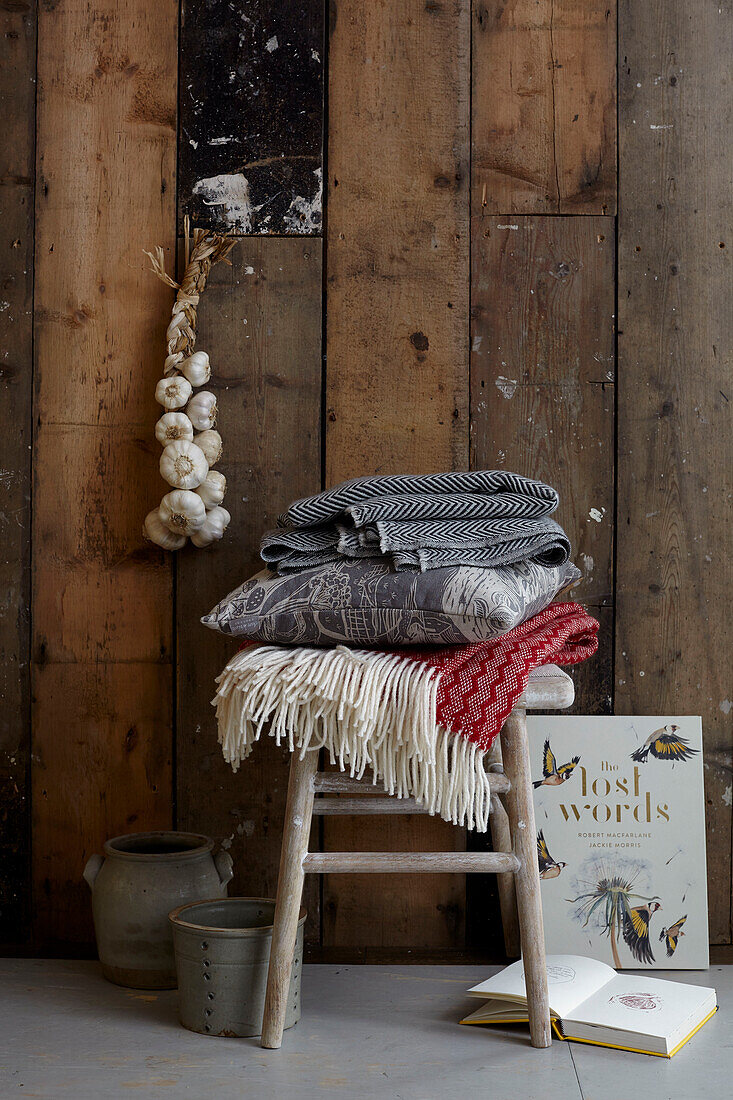 Rustic charm blankets and cushion on stool with wood cladding and garlic