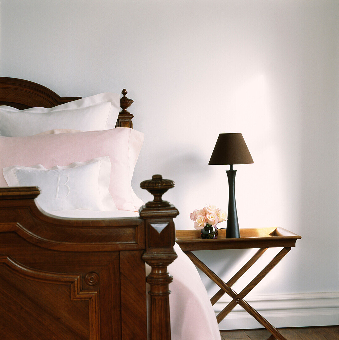 Close up of vintage wooden bed and bedside table and lamp