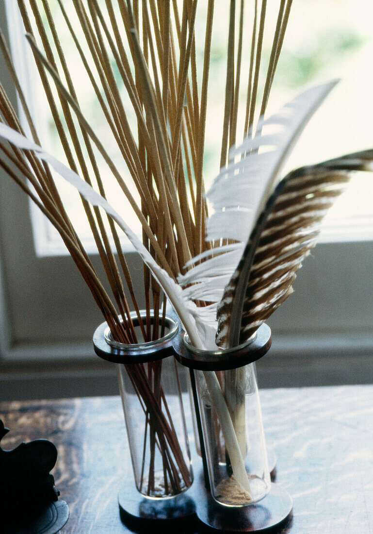 Table top detail with incense sticks and feathers in a vase