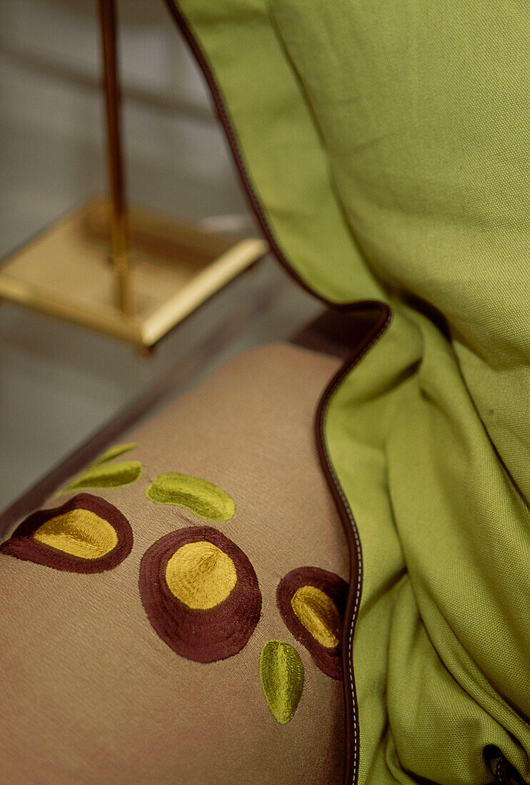 Detail eines bestickten Überwurfs auf einem Sofa mit Kissen
