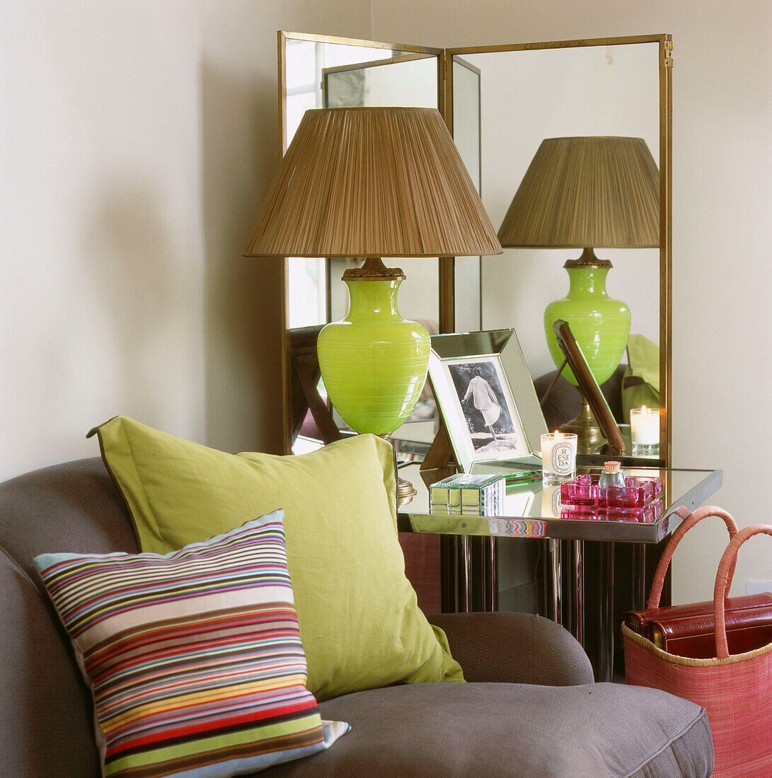 Zimmerecke mit Spiegeltisch, Paravent, hellgrüner Glastischlampe und Glasobjekten