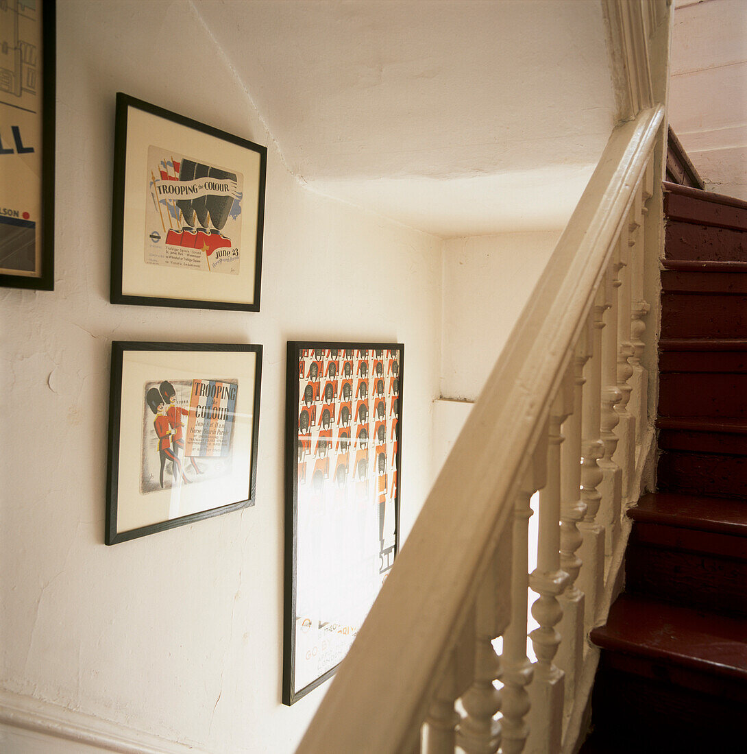 Weißes Treppenhaus mit Pferdedrucken und kardinalrot gestrichenen Treppenstufen