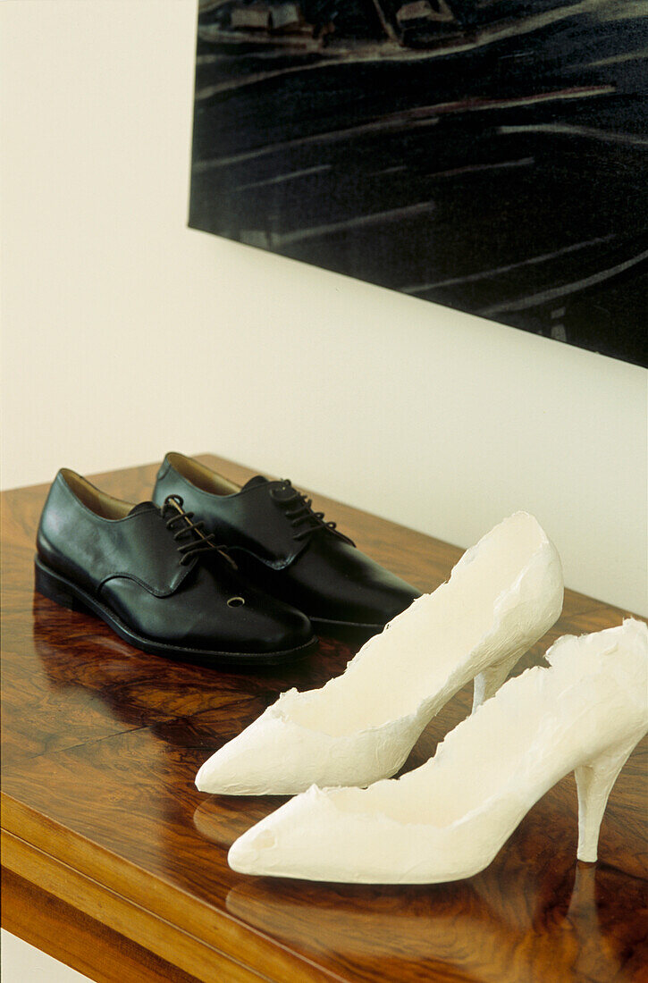 Close up of walnut card table with white lady's high heeled shoes and black men's shoes
