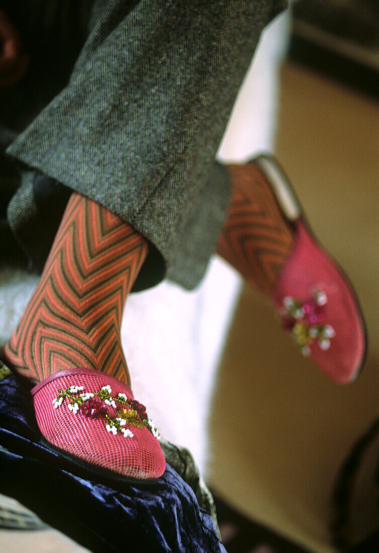 Close up of designer with patterned stockings and embroidered silk slippers