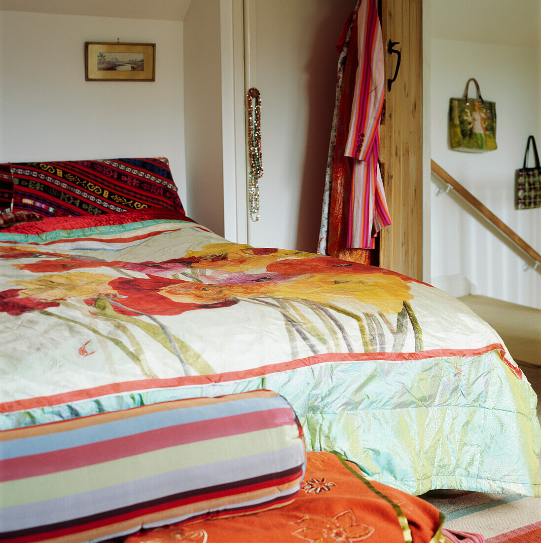 Handbedruckter Blumenstoff auf einer schillernden Seidendecke in einem farbenfrohen Schlafzimmer