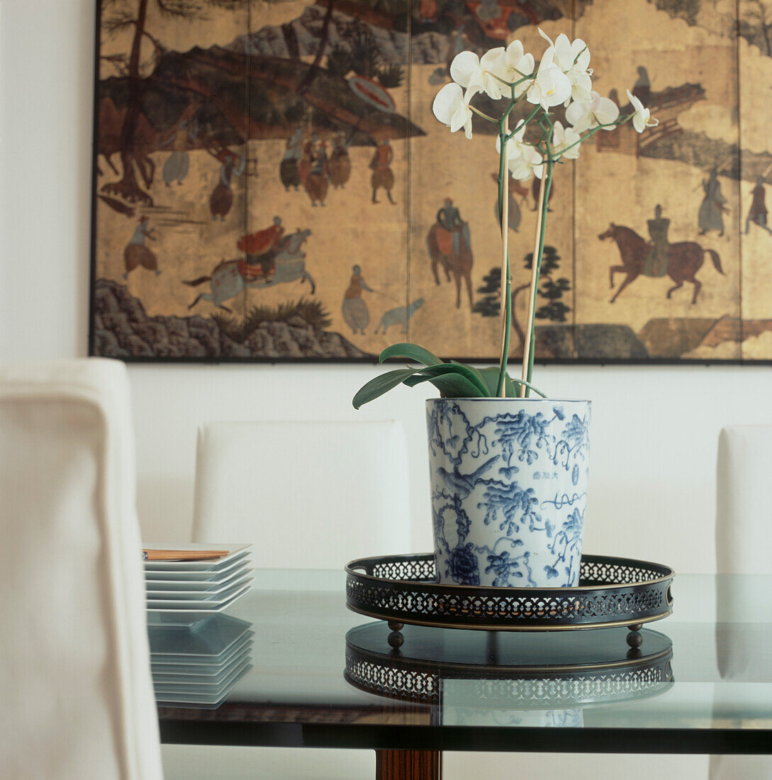 Esszimmer im orientalischen Stil Detail von Glastischplatte Esszimmerstühle Vase Blumenauslage und Gemälde