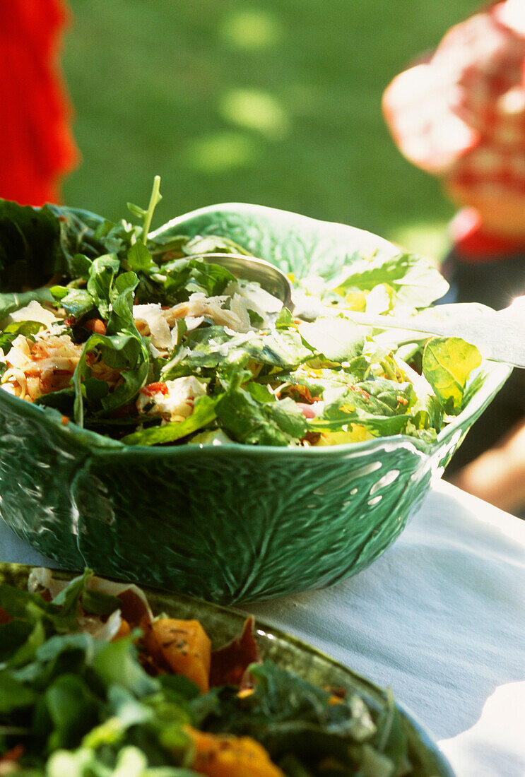 Bunter, frischer Salat in Kohlblatt-Schalen auf einem Tisch im Garten