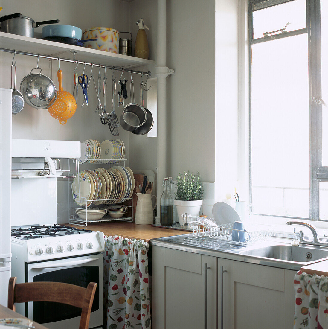 Einfache weiße Küche mit Ikea-Schränken und Hängeschiene mit Töpfen und Pfannen