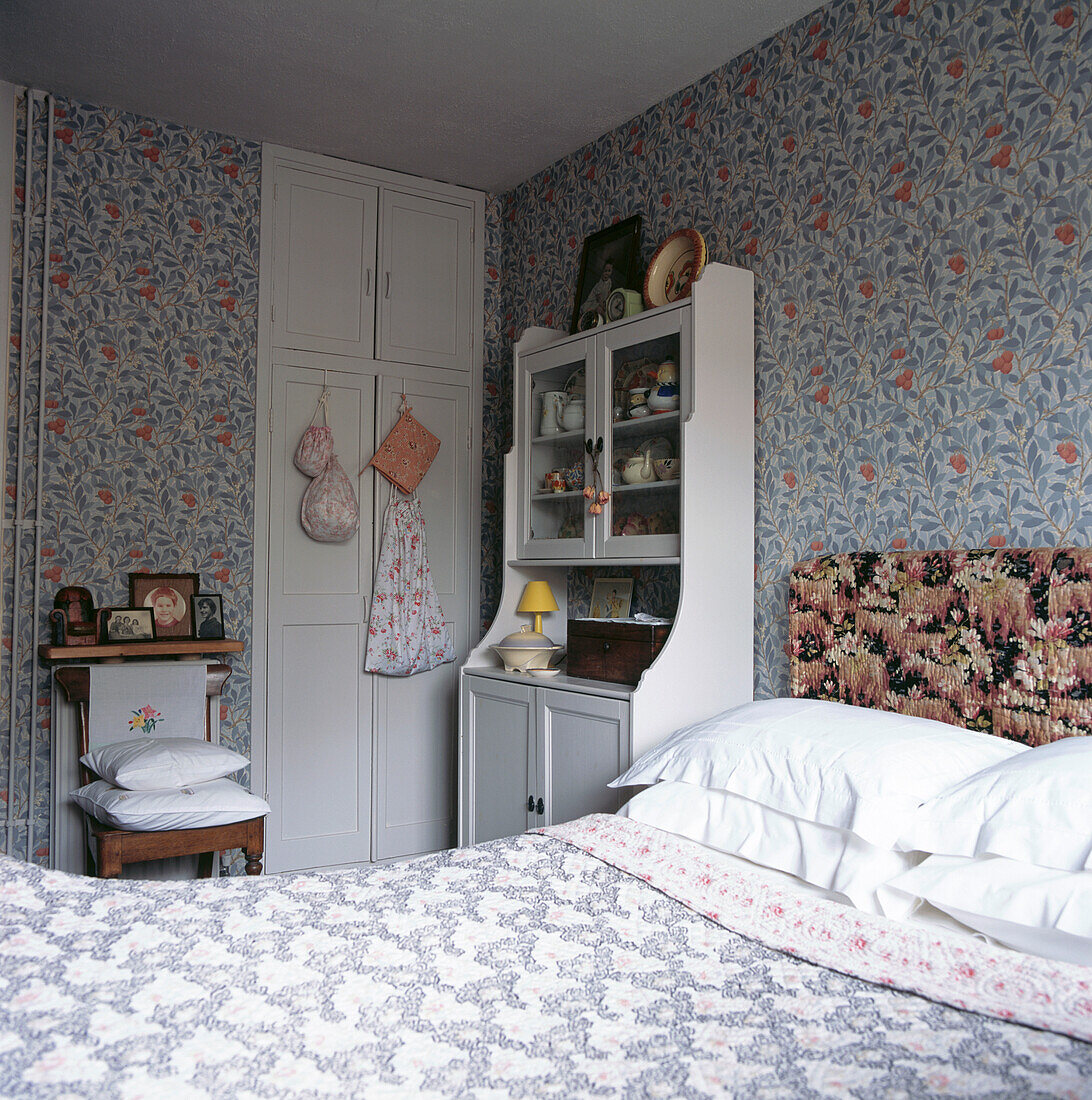 Blue and white bedroom with William Morris style wallpaper and off-white dresser