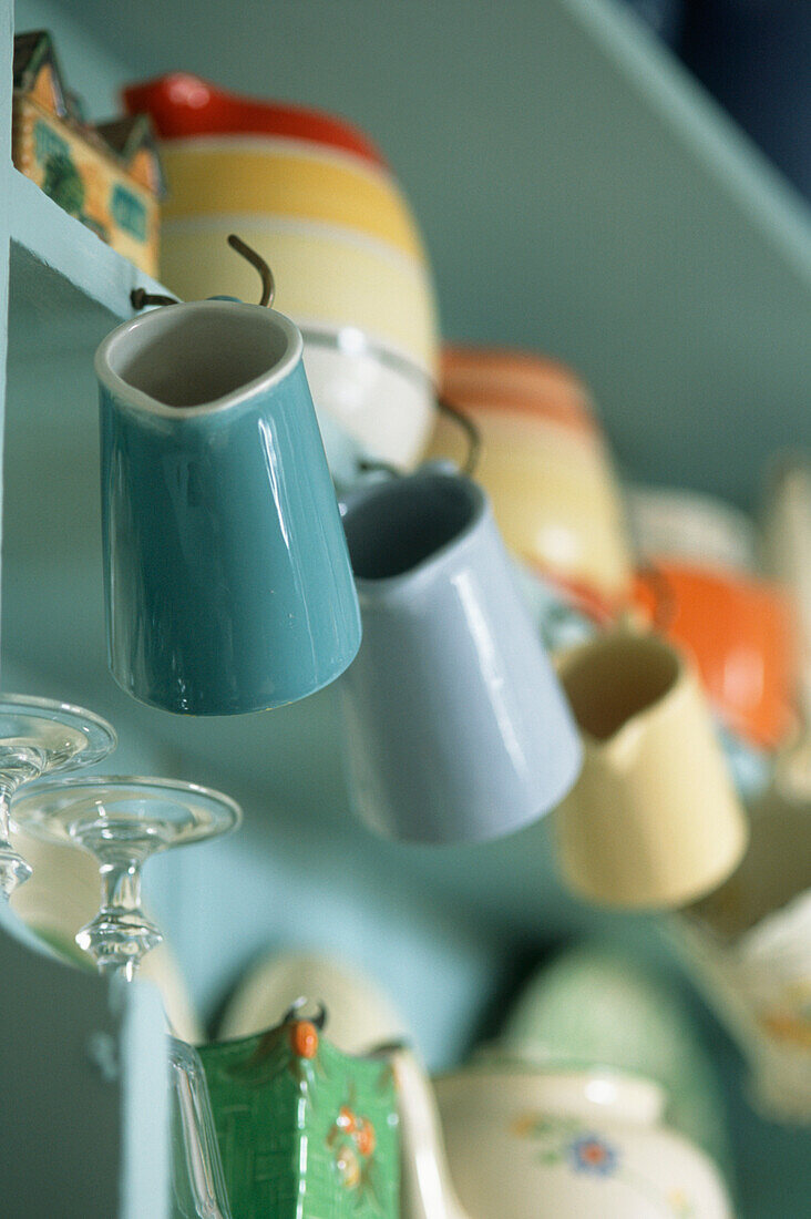 Keramikkrüge auf einem hellblauen Regal in einer Küche