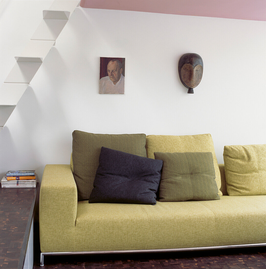 Ein blassgrünes italienisches Sofa neben einer minimalistischen Treppe aus weißem Metall im Wohnbereich im Erdgeschoss