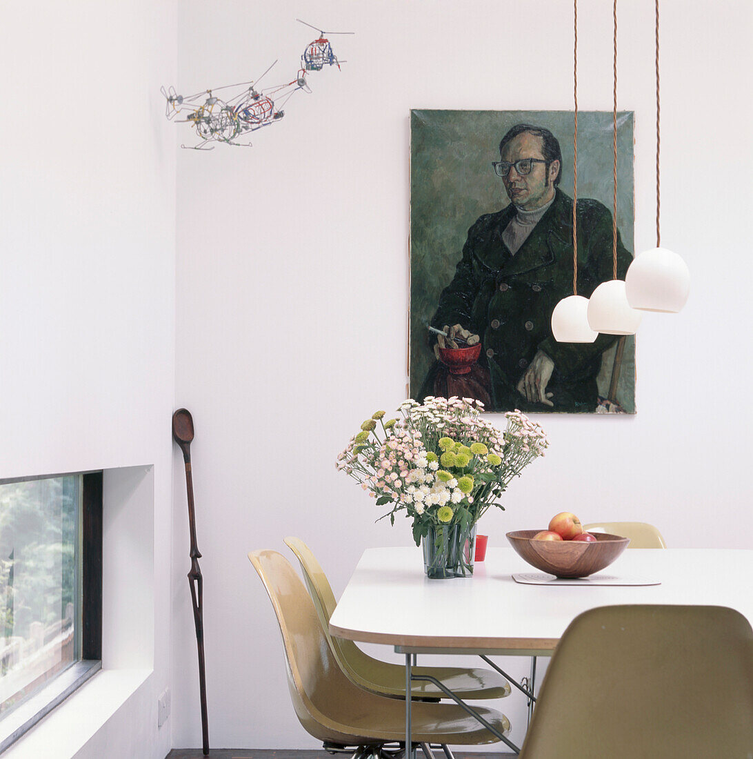 Ecke des Esszimmers mit originalen Eames-Stühlen aus Fiberglas am weißen Esstisch und niedrigen Deckenleuchten