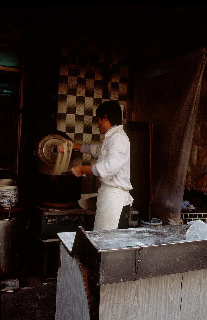 Chinesischer Mann kocht Nudeln auf einem Straßenmarkt in Shanghai, China