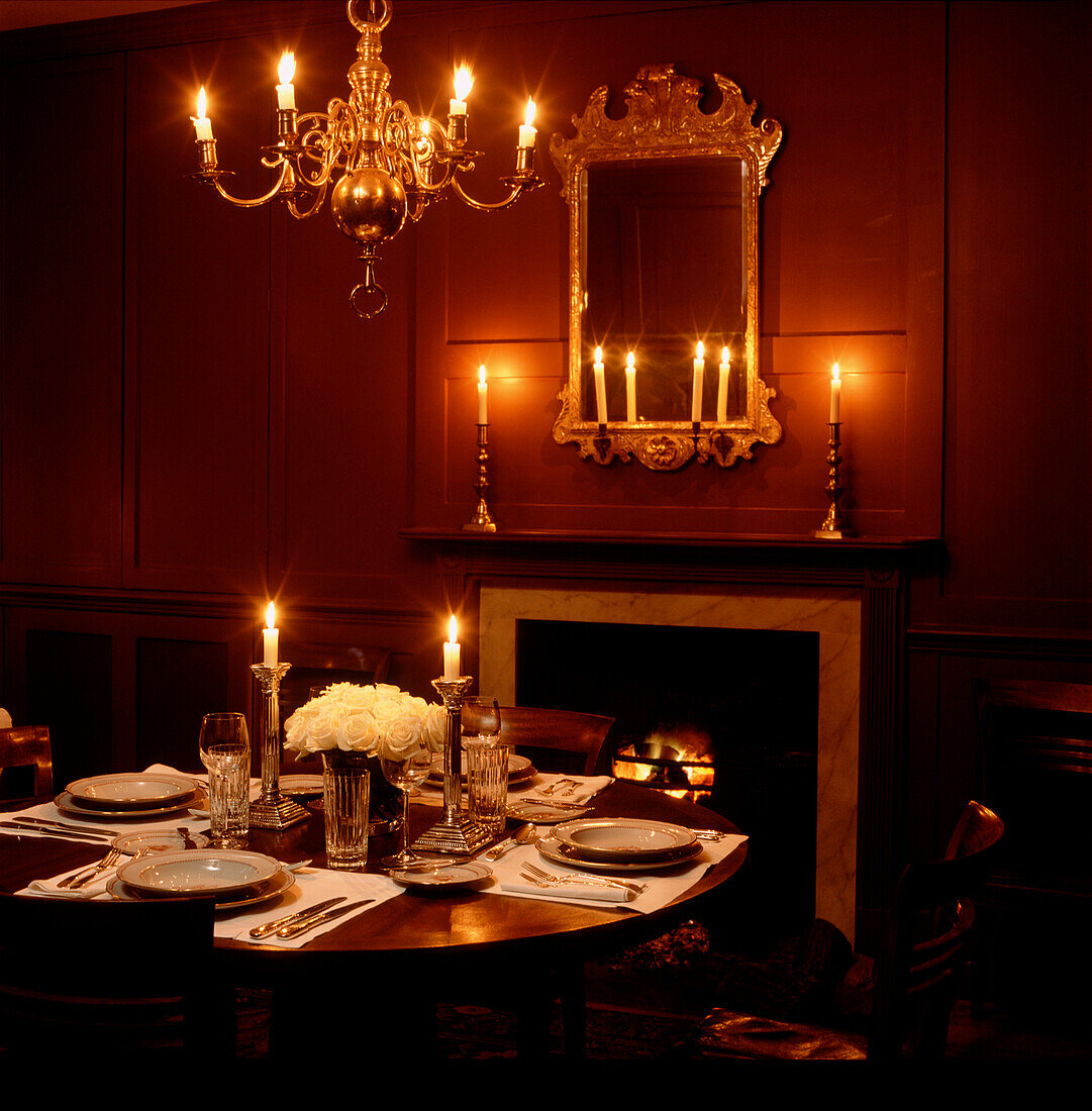 Elegant candlelit dinner in reddish brown wood panelled dining room