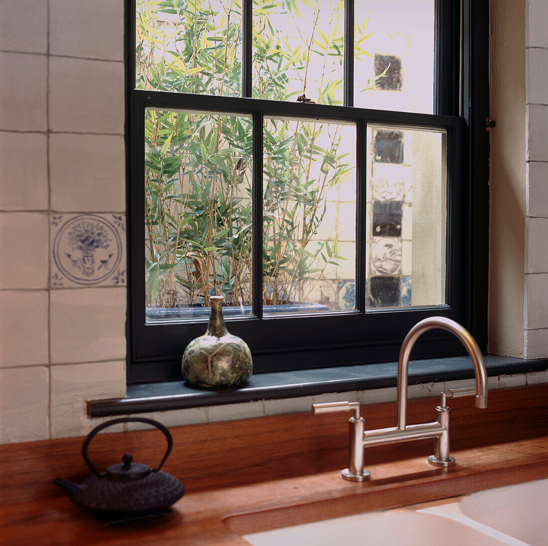 Kitchen sink in tiled kitchen with view of lightwell and bamboo plants 