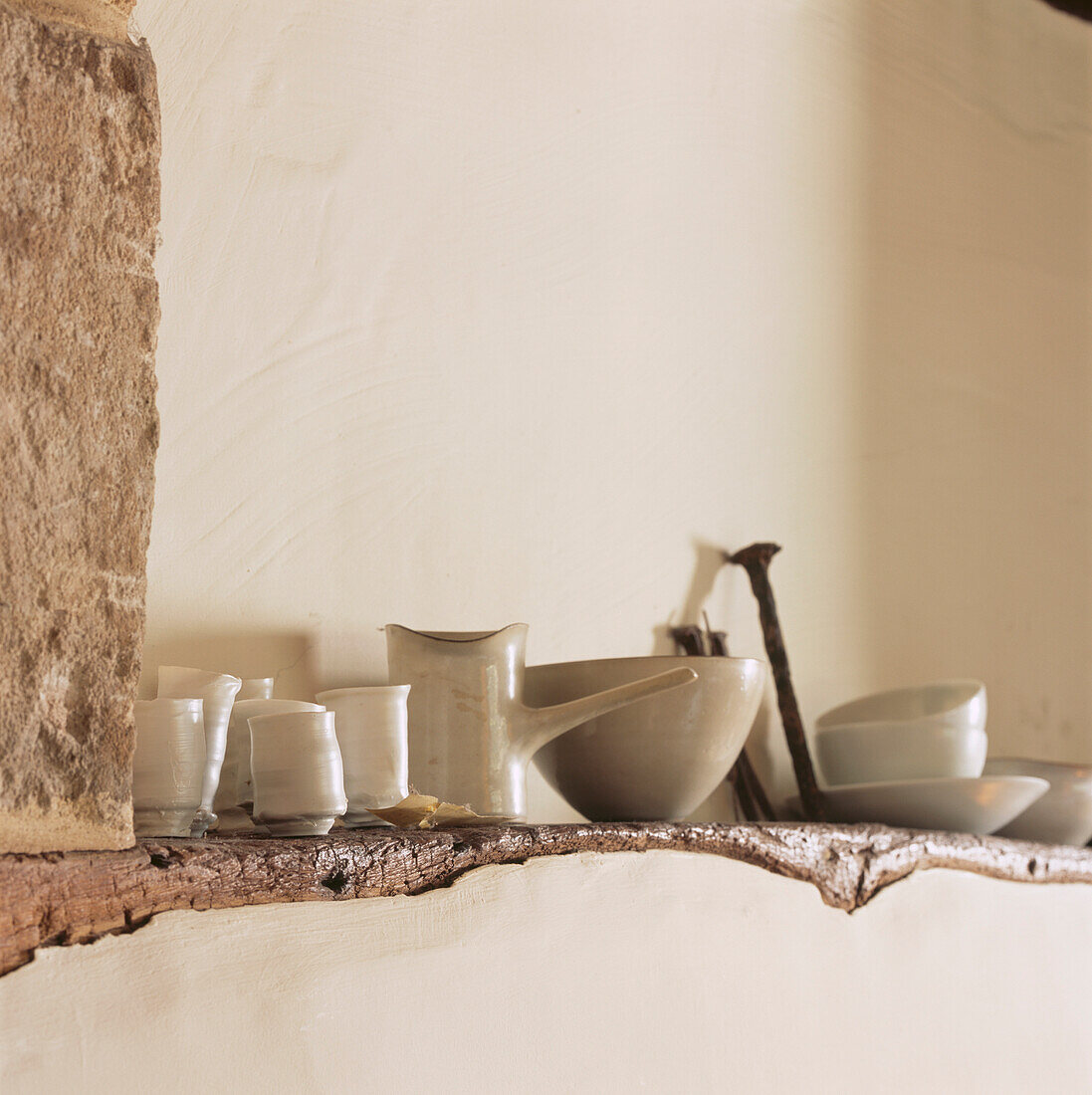 Glasierte Keramiken auf einem Holzbalken in einer verputzten Wand