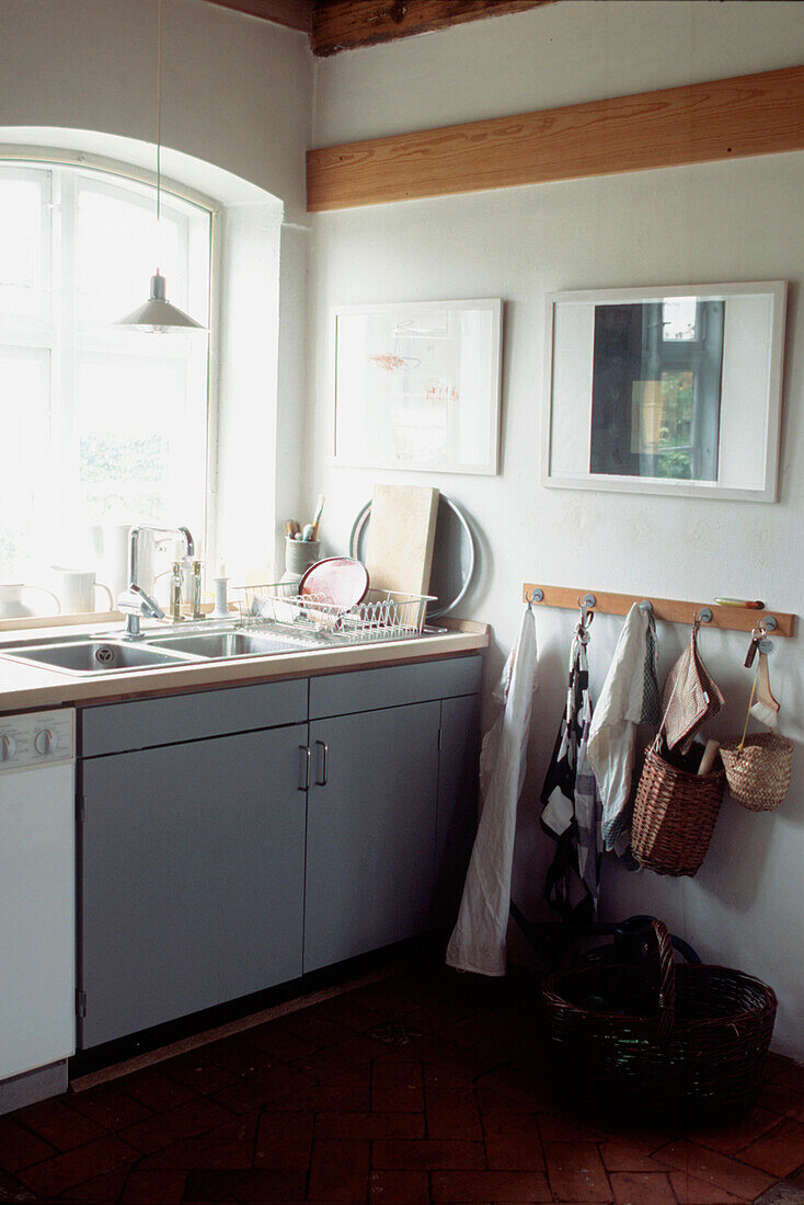 White modern country kitchen with grey storage units kitchen sink and brick stone floors