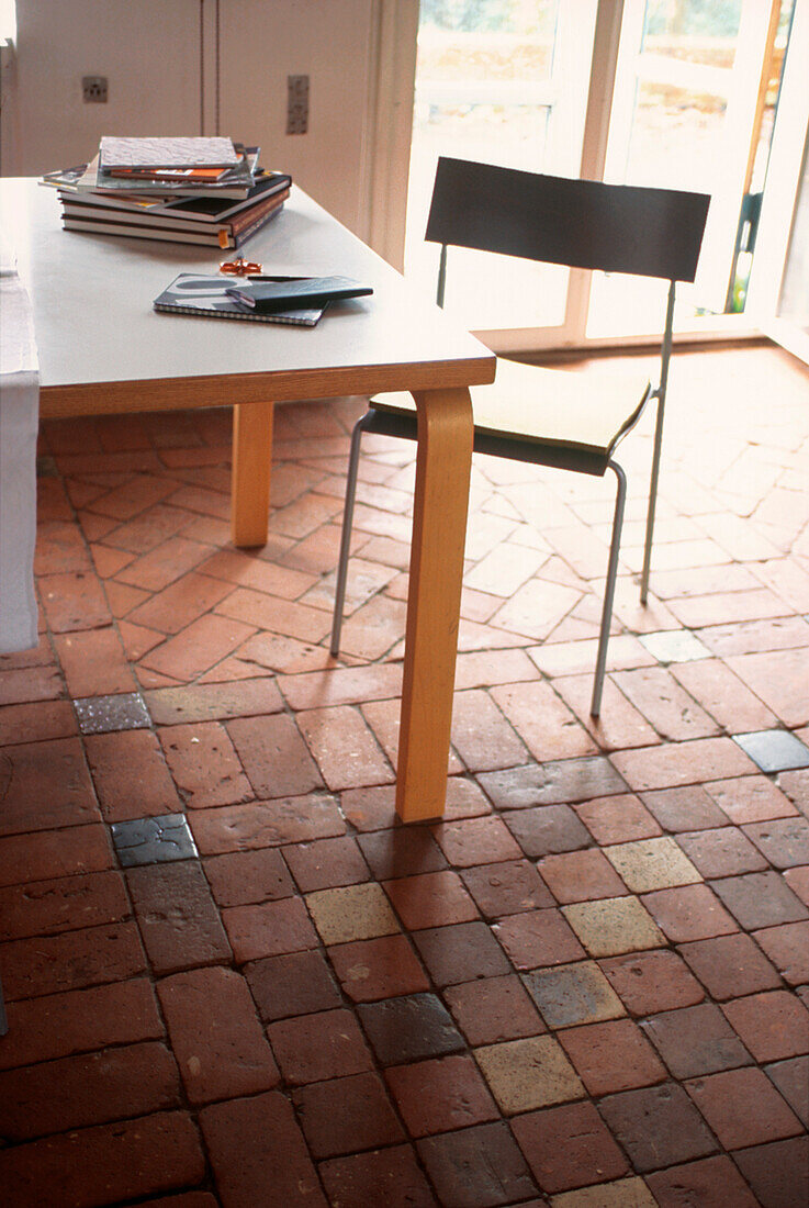 Esszimmer mit Tisch und Stuhl und braunem Ziegelsteinboden