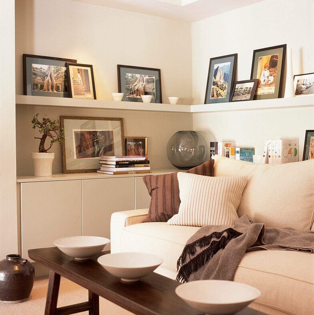 Wohnzimmerecke in Cremetönen mit Einbauschrank und Regalen