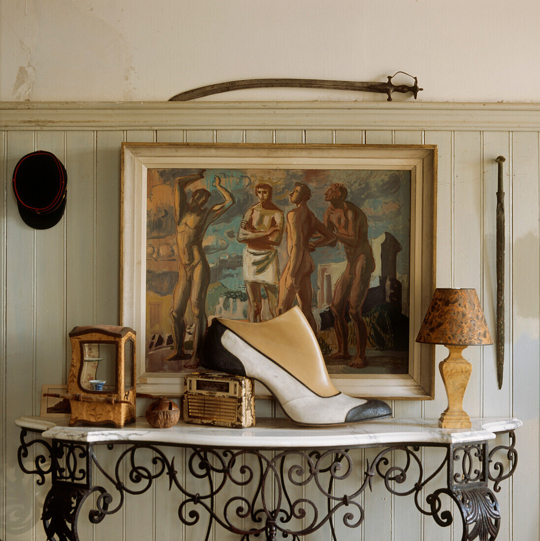 Beistelltisch mit Marmorplatte und gusseisernen, verzierten Beinen mit einer Sammlung von Ornamenten in einem Flur mit gestrichenen, getäfelten Wänden