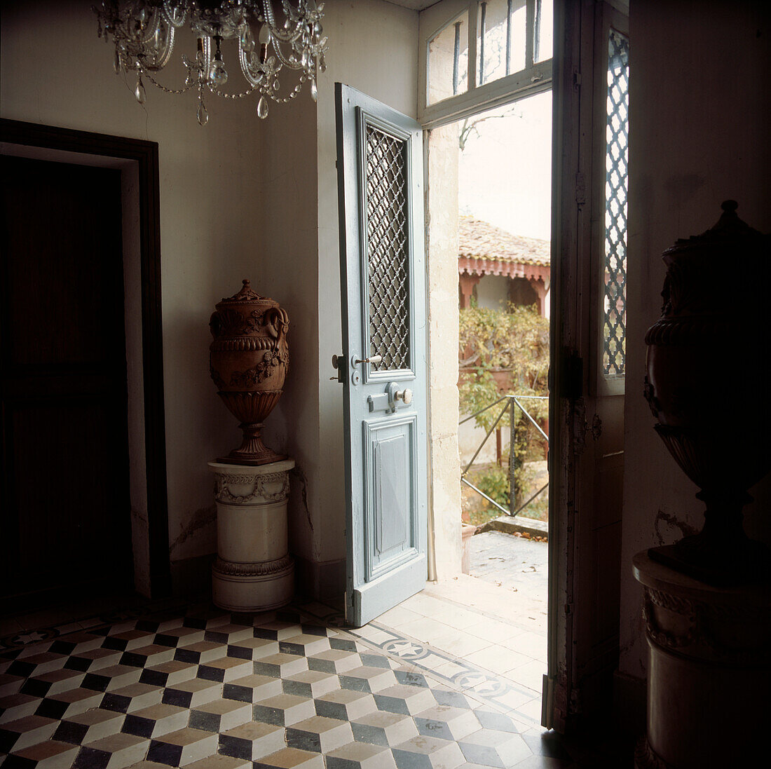 Entrance hall of a period French chateau with open double front doors and checked stone floor