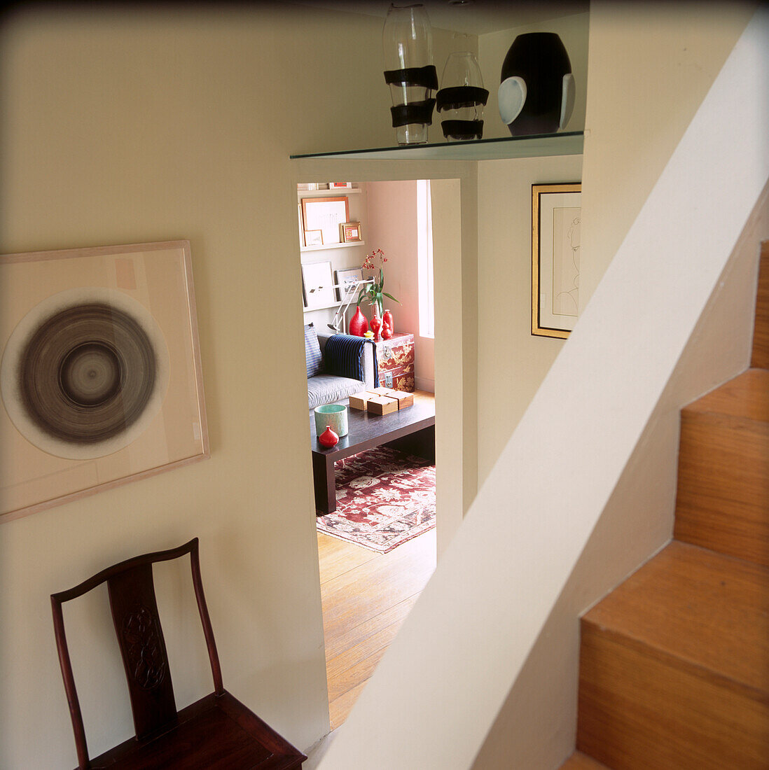 Blick über die Treppe hinunter ins Wohnzimmer mit Glasvasen auf einem hohen Regal