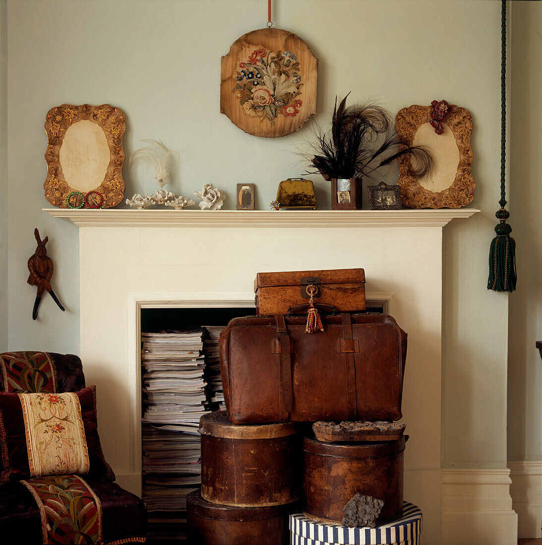 Viktorianischer Kamin, gefüllt mit Zeitschriften und Erinnerungsstücken, davor Hutschachteln und Lederkoffer