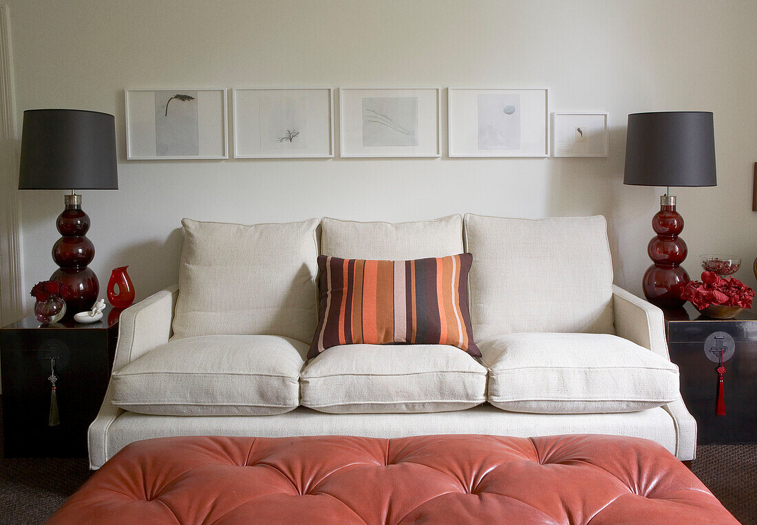 Dreisitzer-Sofa im Wohnzimmer mit symmetrischem Dekor und rotem Leder-Ottoman
