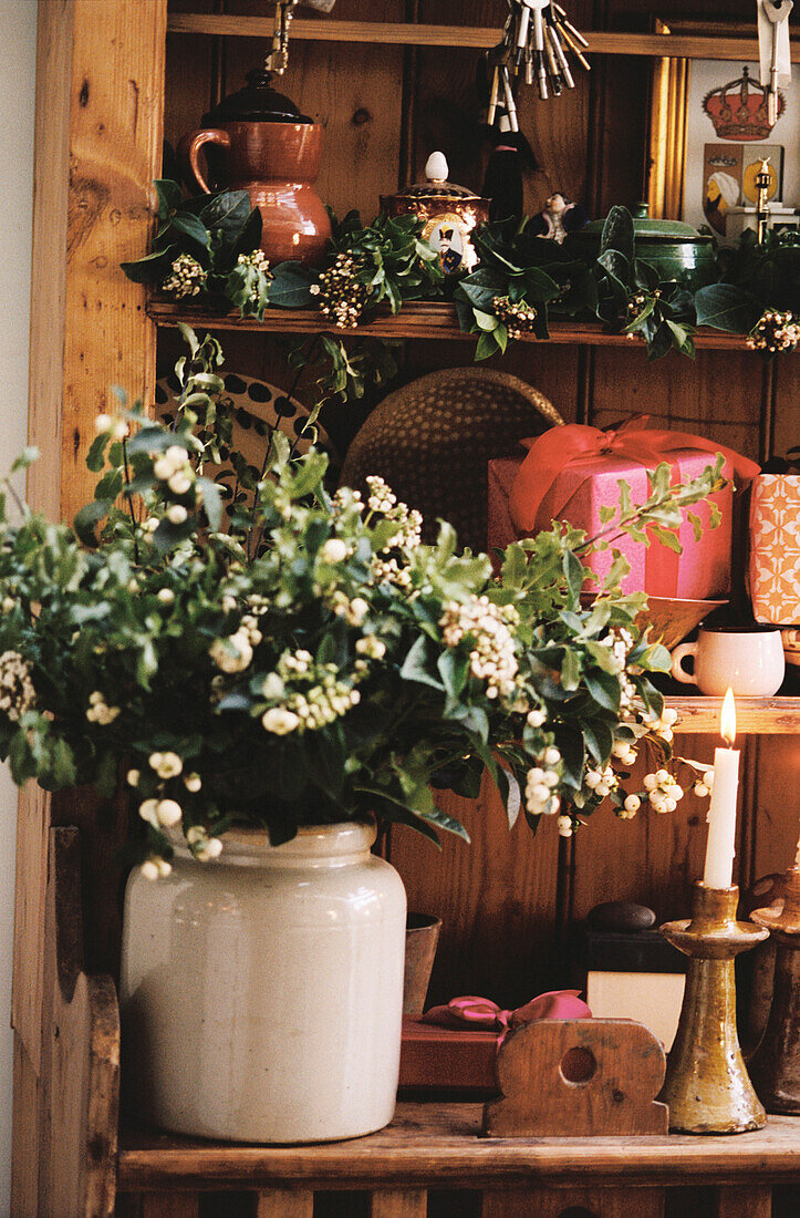 Stilleben mit saisonalen Blumen und Weihnachtsgeschenken auf einer Kommode