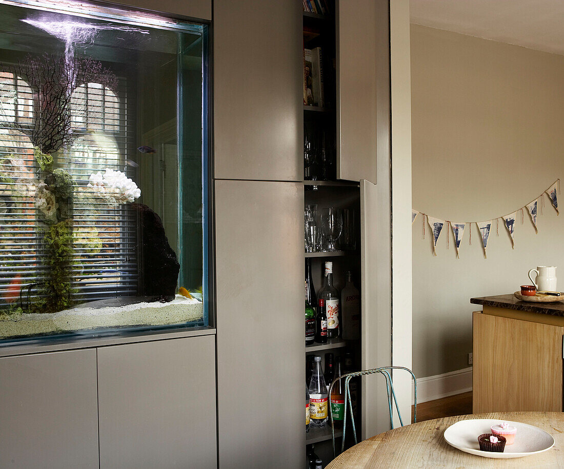 Aquarium built in to partition wall in the kitchen with additional storage cupboards