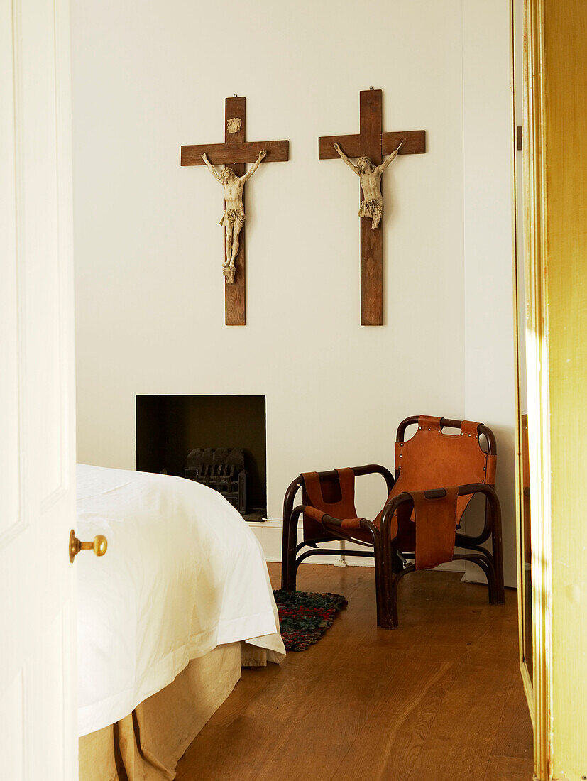 Bedroom with chair and pair of crucifix hanging on the wall