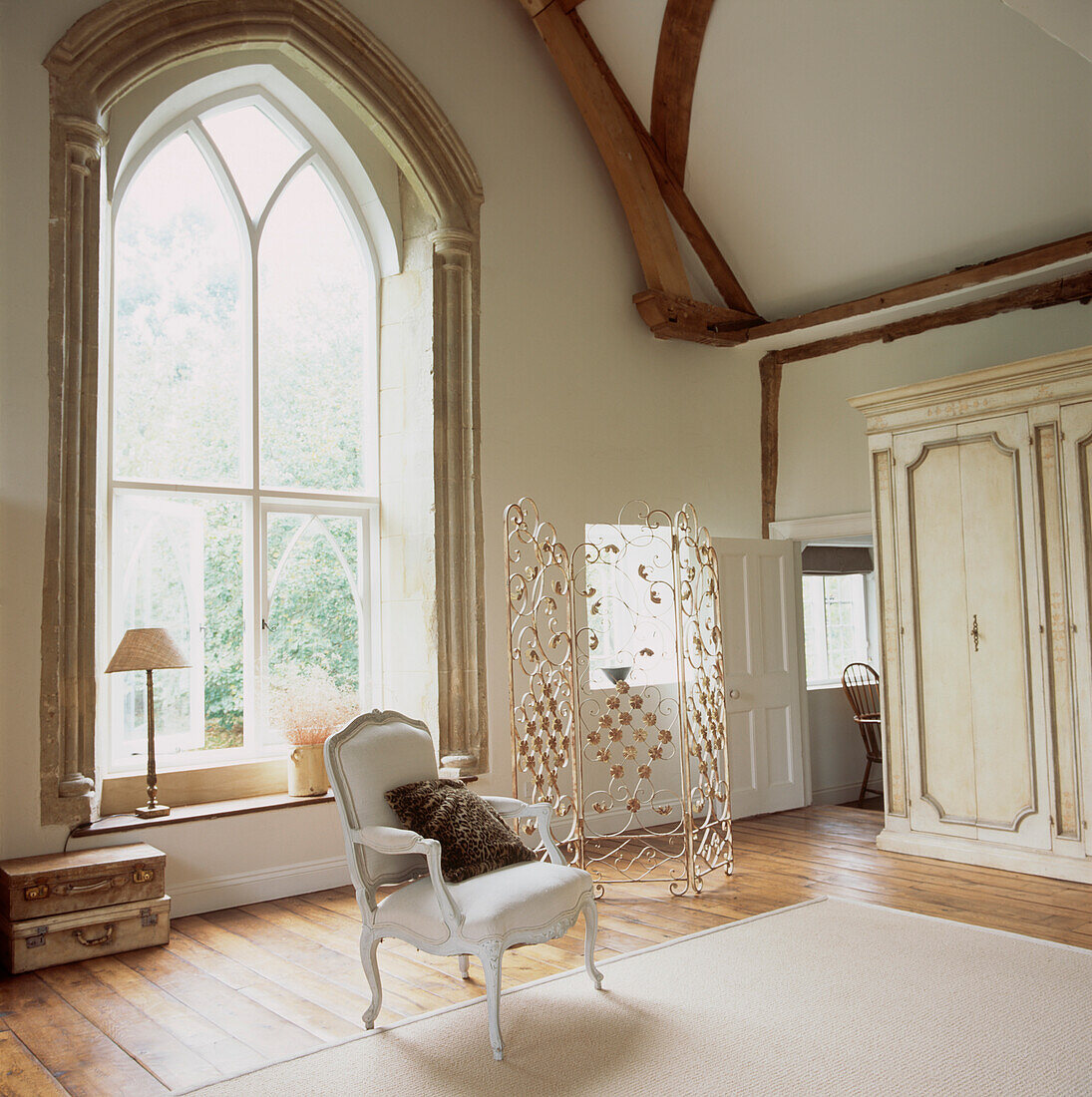 Wohnzimmer mit Holzbalkendecke und großem Bogenfenster in neutralen Farben