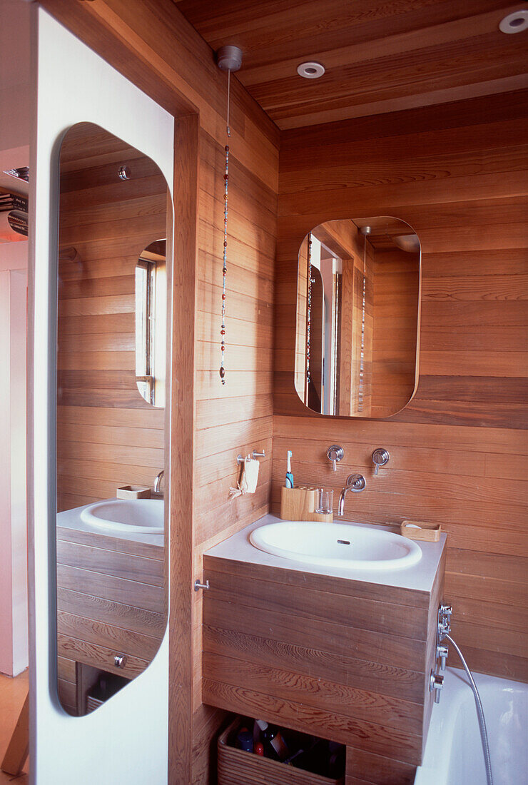 Kleines modernes Badezimmer mit dunkler Holzverkleidung und Spiegeln