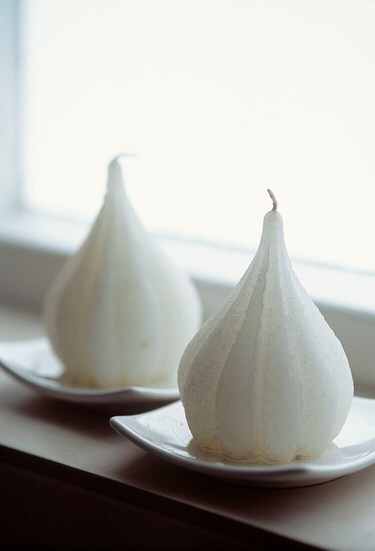 Weiße Kerze in Form einer Birne auf einer Fensterbank