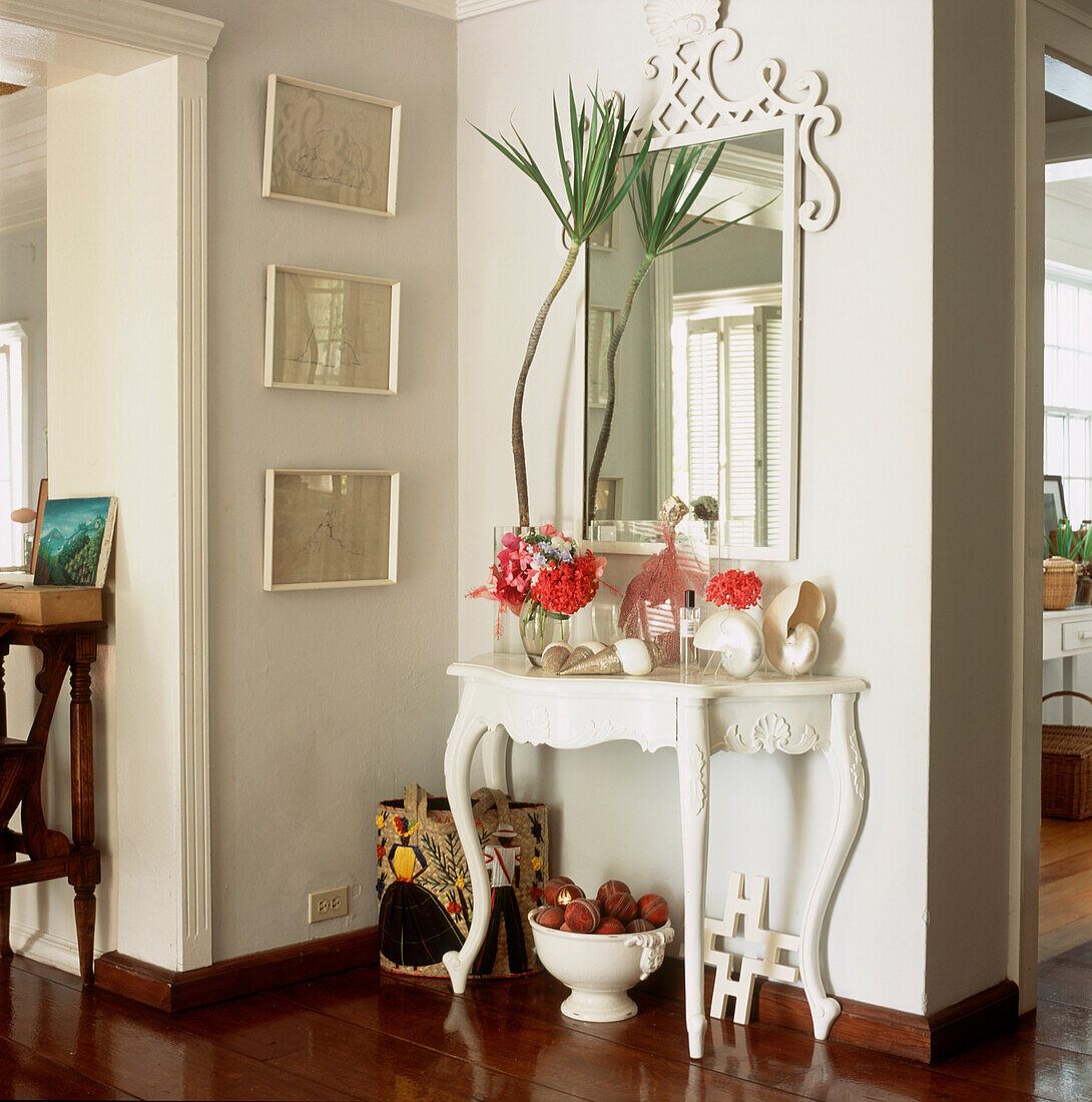 Hallway in white with mirror and painted console table with shells and plant