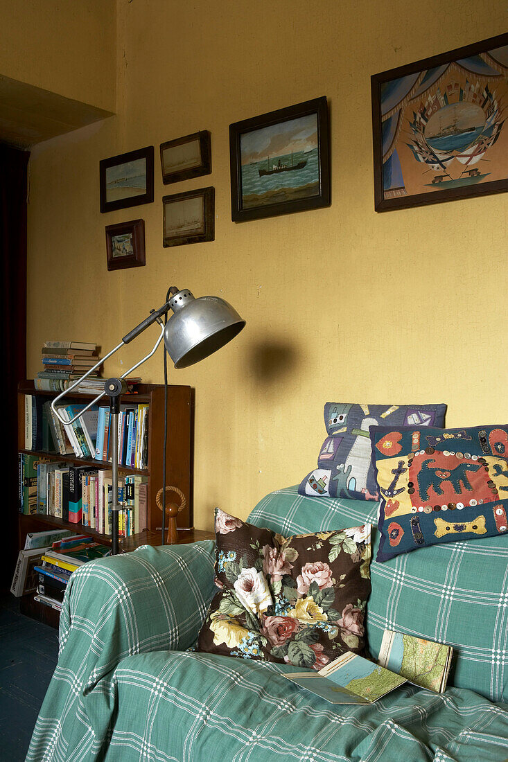 Tiny sitting room painted in yellow and with sofa dressed in Welsh blankets and vintage textiles