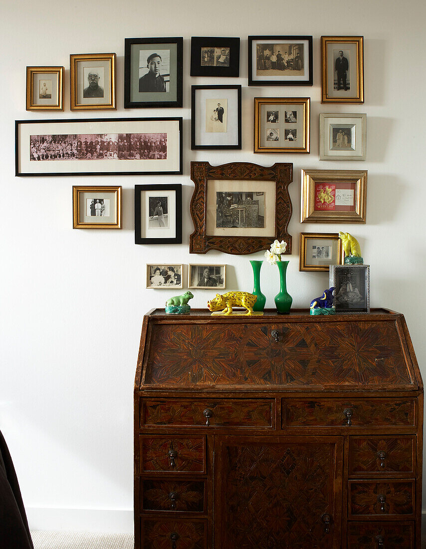 Antique bureau with collection of framed family photos and memorabilia