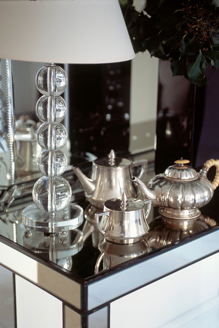 Silver tea set on mirrored console with bubble glass lamp